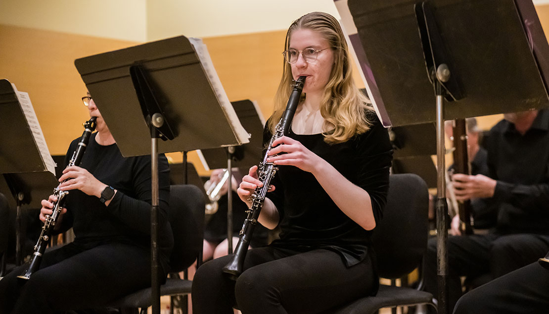 A student playing the clarinet during a Ӱҵ Wind Ensemble concert.