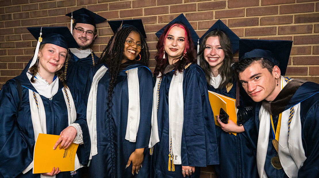 Six diverse students wearing graduation cap and gowns
