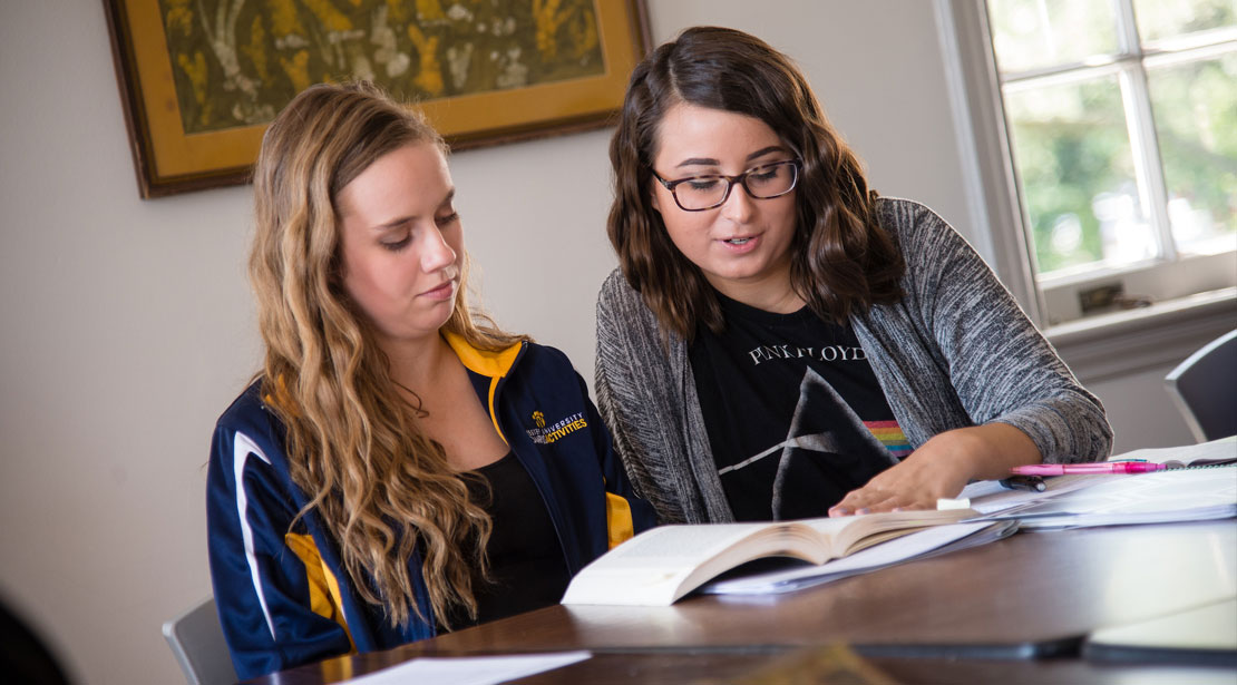Two female students discussing a book