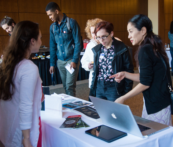 People talking to student at their portfolio display table