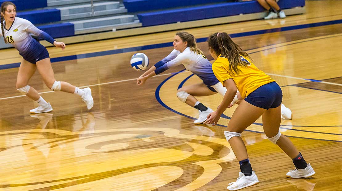 Student pikes the volleyball in the middle of a game.