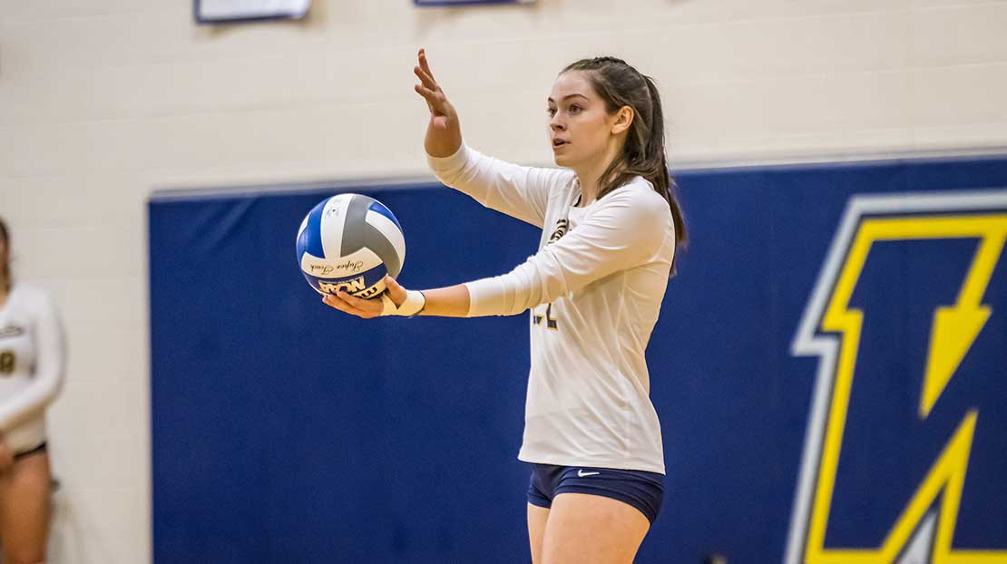A girl prepares to serve during a volleyball game.