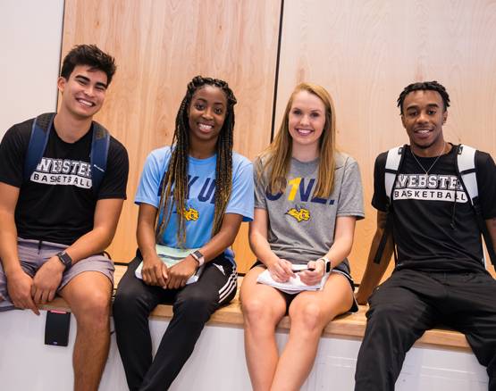 four Webster students sit on bench together, smiling