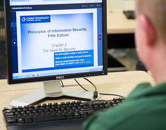 Student at computer screen that reads "Principles of Information Security, Fifth Edition; Chapter 2: The Need for Security"