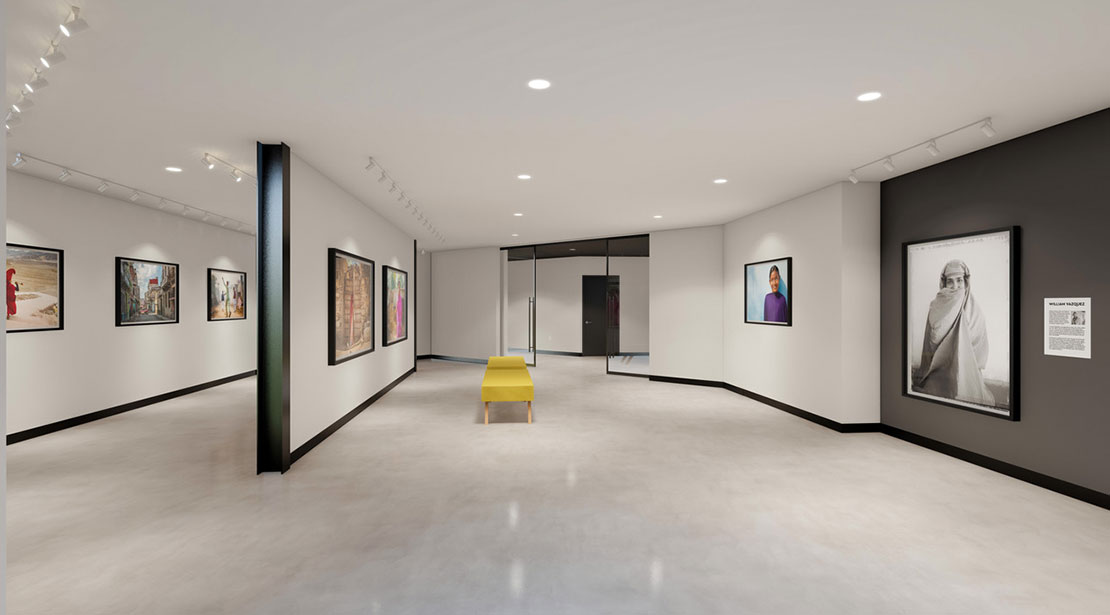 Kooyumjian Gallery with white walls covered in large photos, one gray accent wall and long bench