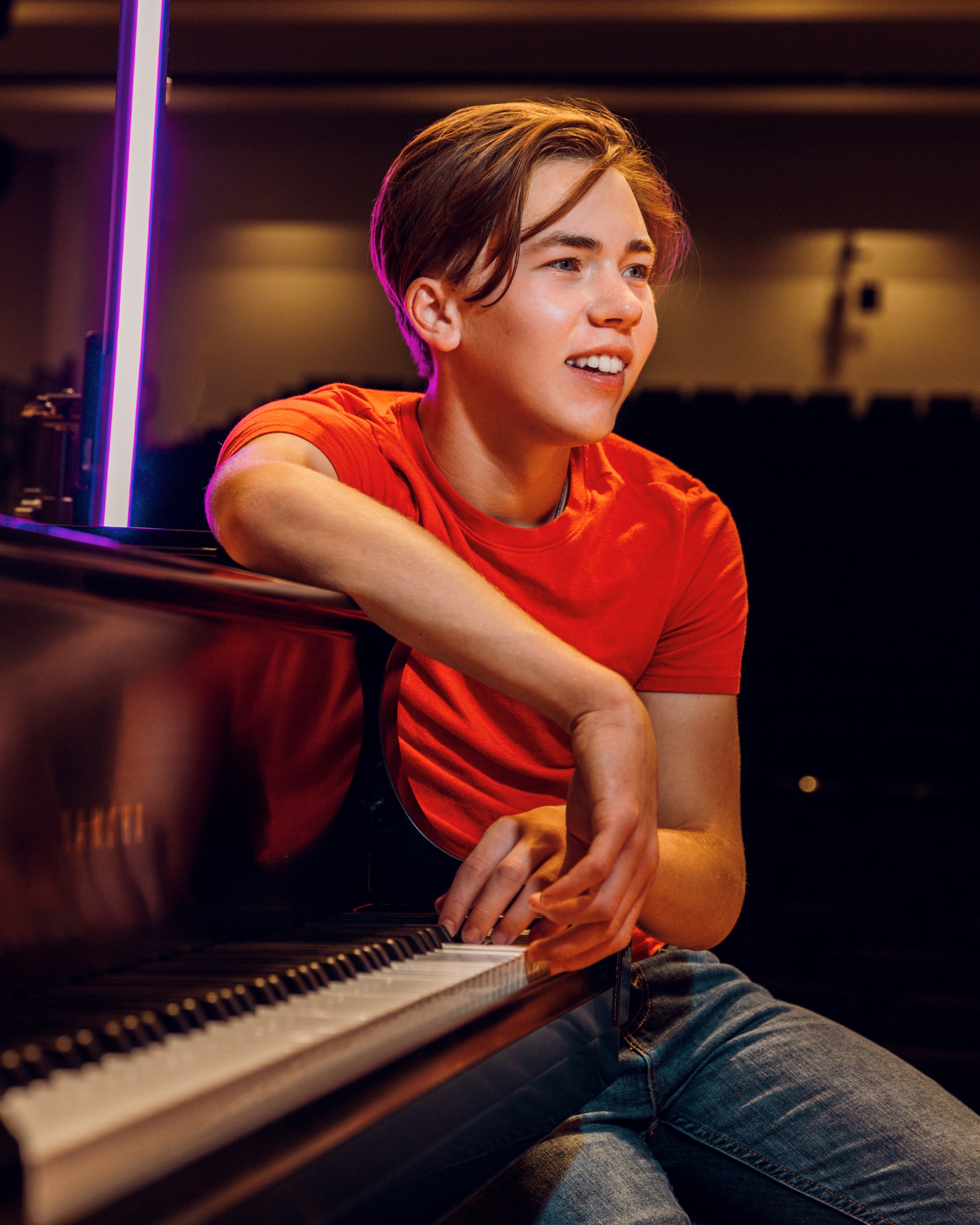 Young boy in red shirt sitting at piano