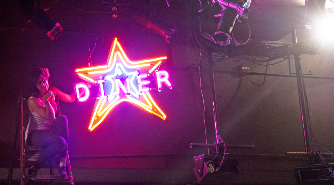 Student working with neon DINER light for stage production