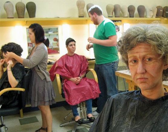A group of students work on makeup and wigs.