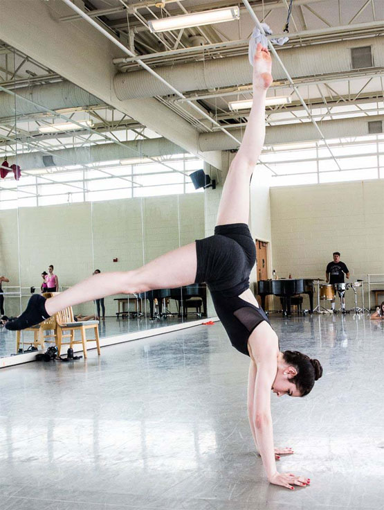 Dancer in handstand with legs extended in opposite directions