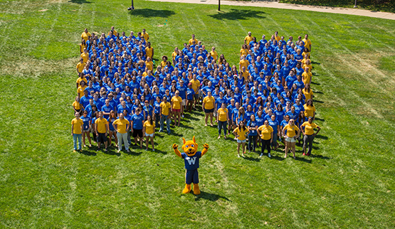 students form a large blue W with yellow outline on lawn, Gorlok mascot in front