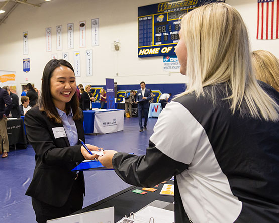 Student in suit at career expo shaking recruiter's hand