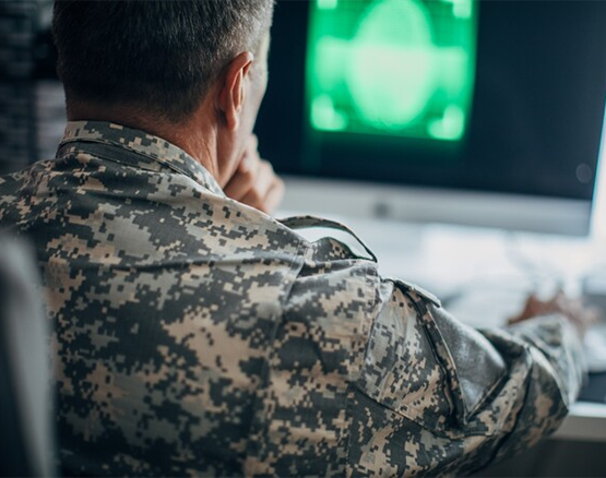 Male member of the military wearing Army fatigues, working on an online course on his computer.
