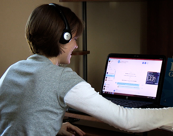 Female student with headphones working at a laptop on an online class. 