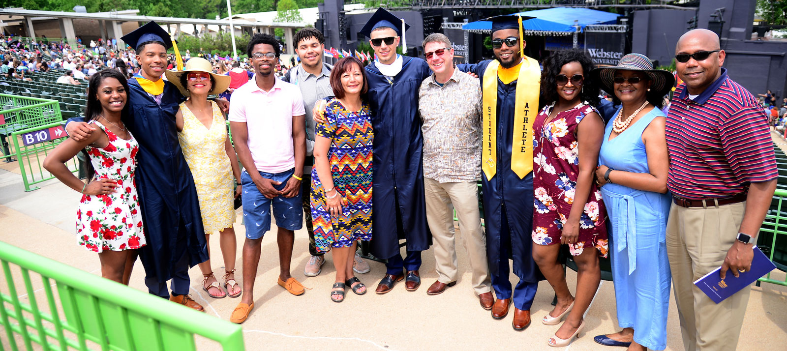 Three graduates pose together with their families at graduation.