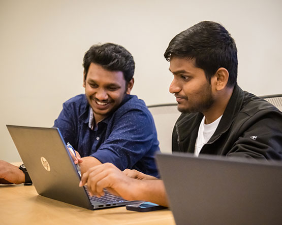 Two students working together on laptop