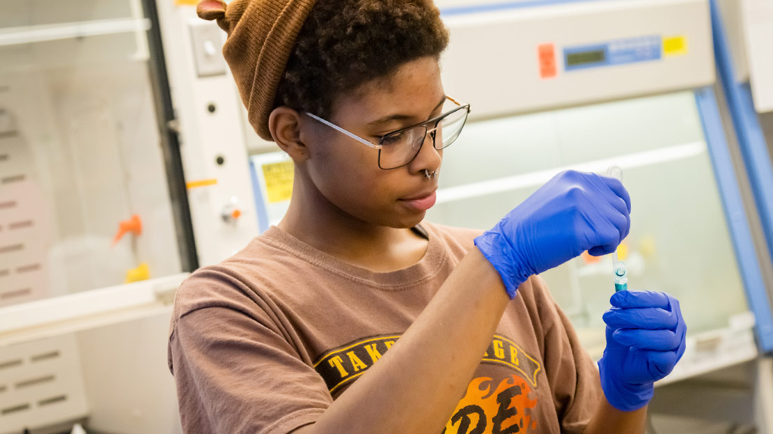 A student examines a sample in a tube.
