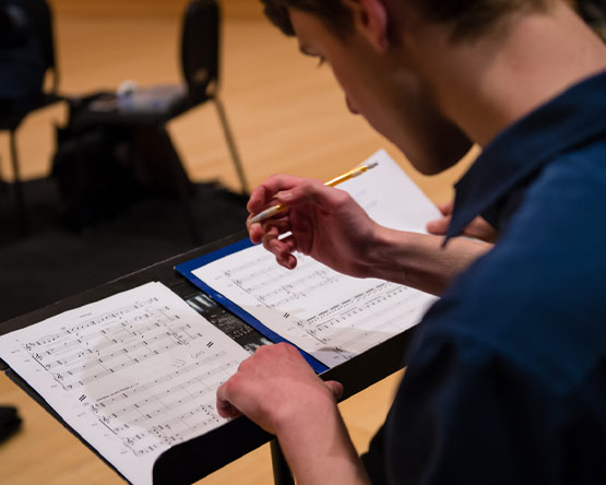 A student notates music on music composition paper.